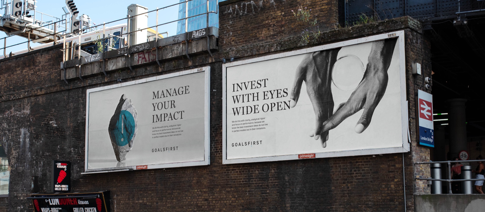 Two billboards on a brick railway viaduct at London Bridge: Manage your impact with a standing stone holding a cyan disc, and Invest with eyes wide open with two hands passing a glass lens